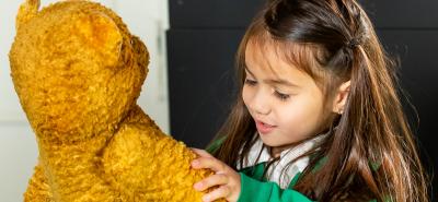 Pupil in uniform playing with a vintage teddy bear