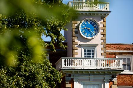 close up of clock tower with foliage in foreground