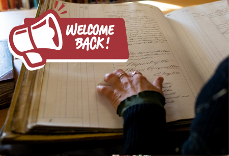 hand tracing over text in an old register with a callout sign saying 'welcome back'