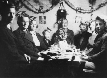 Black and white photo of people during WW2 sat down for their christmas dinner