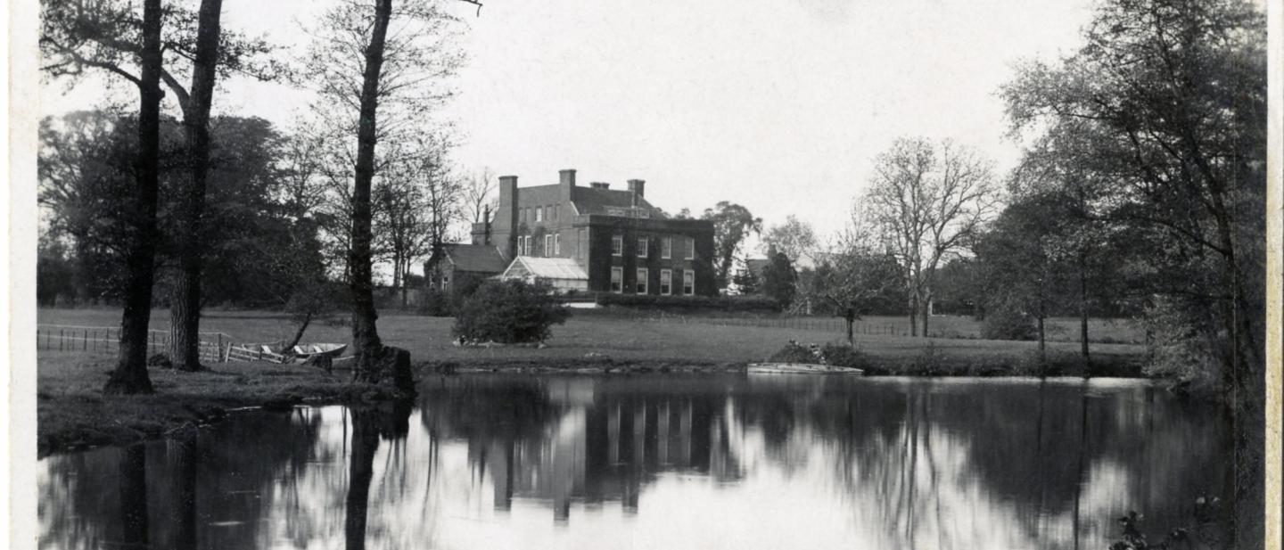 A manor house with a lake in front, from the late 1800s
