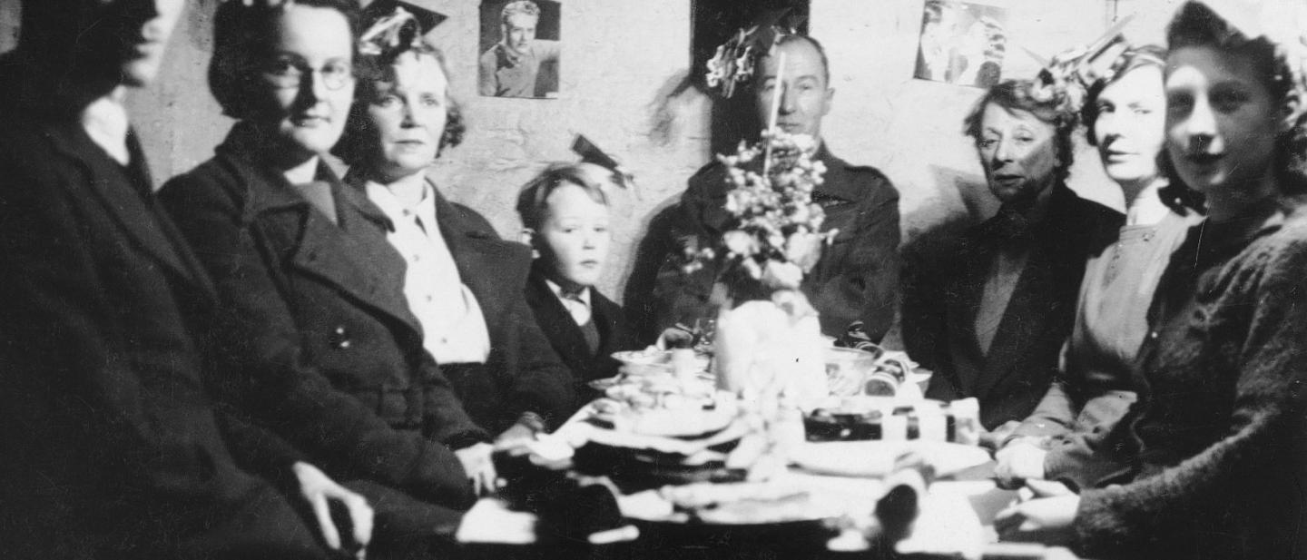 Black and white photo of people during WW2 sat down for their christmas dinner