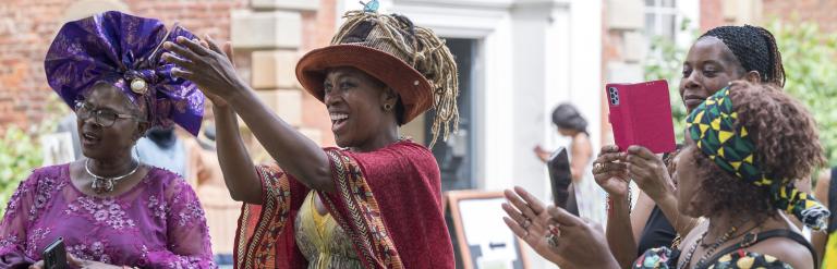 people smiling and clapping at a windrush day celebration at bruce castle