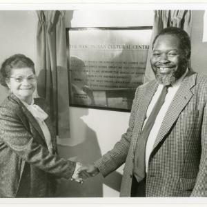 Bernie Grant and woman shaking hands with the opening plaque for the West Indian Cultural Centre in the background