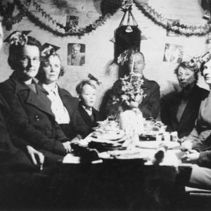 Black and white photo of people during WW2 sat down for their christmas dinner